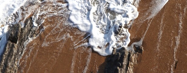Textured Background. Sea foam splashed on the shore. Top view. Abstract composition. Sand. Waves....