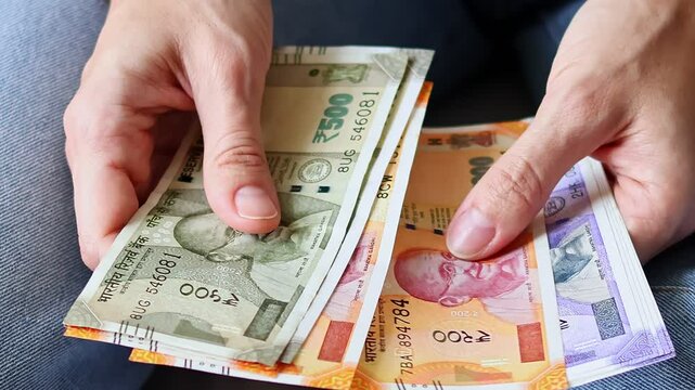 Close up view of woman's hands holding brand new indian 100, 200, 500 rupees banknotes INR. Concept of saving money, cash settlement, financial literacy and planning.