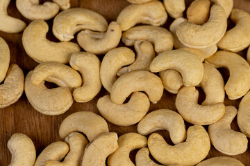 large cashew nuts are scattered on a larch board