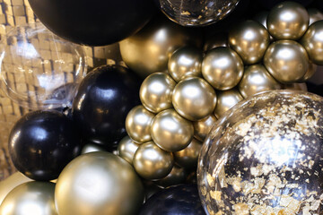 Decorative birthday photo wall. Gold and black balloons texture. Shiny balloon backdrop for New Year's Eve celebrations and photo shoots. Glittering ornament.