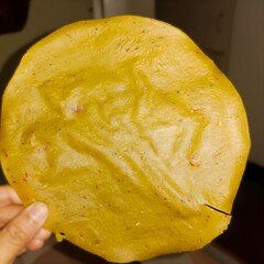 close-up of a sun-dried, homemade sweet potato papad, showcasing its golden-yellow hue and slightly uneven texture