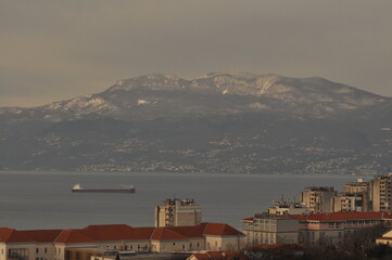 Rijeka city panoramic wiev of Kvarner gulf, ship entering in harbour and in background Ucka mountain covered with snow