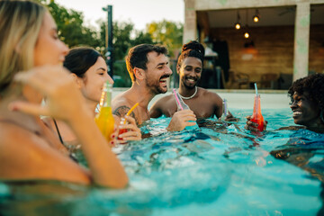 Friends enjoying drinks in swimming pool at summer party