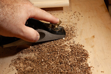 Close-up of a hand using a wood plane on a workbench
