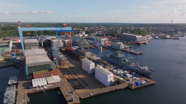 Aerial views capture the Howaldtswerke Deutsche Werft shipyard in Kiel, Germany, showcasing German navy ships under construction, highlighting naval engineering and industrial activity