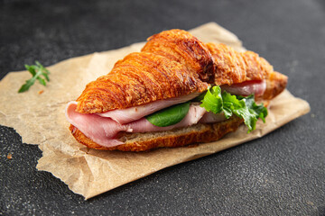 Croissant sandwich ham, cheese, green leaf salad delicious gourmet food background on the table rustic food top view copy space