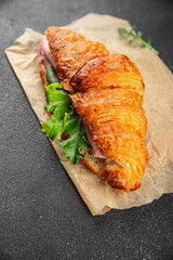 Croissant sandwich ham, cheese, green leaf salad delicious gourmet food background on the table rustic food top view copy space