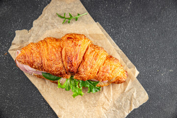 Croissant sandwich ham, cheese, green leaf salad delicious gourmet food background on the table rustic food top view copy space