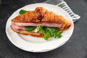 Croissant sandwich ham, cheese, green leaf salad delicious gourmet food background on the table rustic food top view copy space
