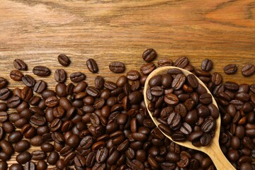 Fresh coffee beans in a wooden spoon on a wooden background
