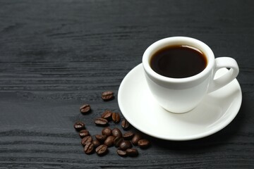 Cup of coffee and fresh coffee beans on wooden background
