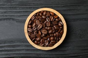 Fresh coffee beans in a wooden bowl on a wooden background