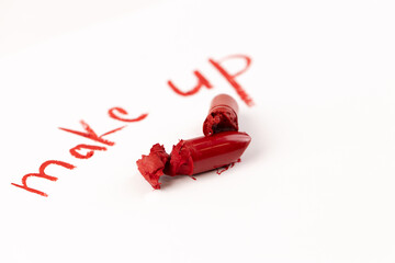 Vibrant Red Makeup Products Showcasing a Creative Display of Broken Lipstick on Paper with the Words 'Make Up' Written in Bold Red Color, Evoking Beauty and Artistry