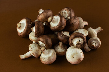 A Close-Up View of a Fresh Pile of Button Mushrooms on a Brown Background Showcasing Their Textures and Colors Perfect for Culinary Inspiration