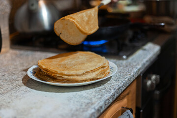 The process of cooking pancakes, a traditional Shrovetide meal.