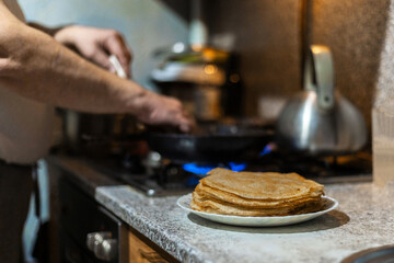 Traditional baking of pancakes for Shrovetide. The process of making delicious pancakes.