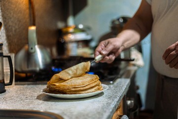 Traditional baking of pancakes for Shrovetide. The process of making delicious pancakes.