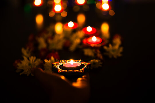 Diwali diyas glowing with warm candlelight and colorful bokeh lights.