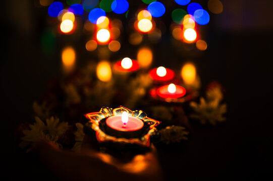 Diwali diyas glowing with warm candlelight and colorful bokeh lights.