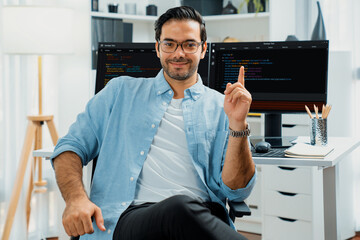 Profile's smart IT developer looking camera to pose wearing glasses against on software development...
