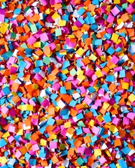 Close-up vibrant pile of square-cut confetti in rainbow colors, forming a cheerful and textured surface, perfectly suited for festive backgrounds, party invitations, and joyful greeting designs