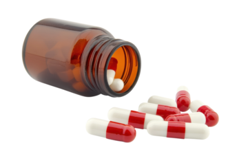 Bright red and white capsules spilling from a brown bottle on a clean white surface isolated on transparent background