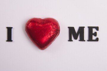 I Love Me, uses the Red Chocolate heart to represent the word love Black wooden letters on a white background, 