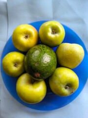 six green apples and avocado on a blue plate