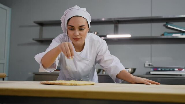 Chef sprinkling cheese on pizza in restaurant