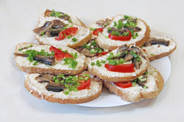 toasts with sprats and green onions on plate. Sandwiches for breakfast