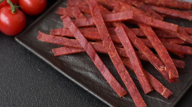 Jerky dried fish sticks with salt and spices on a dark concrete background