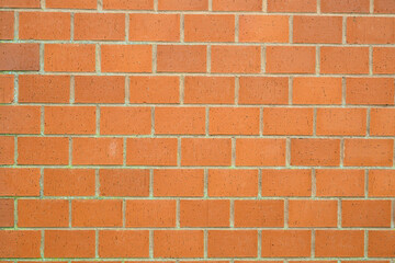 A well-structured wall made entirely of red bricks arranged in a consistent pattern. This surface showcases a smooth texture that can inspire various architectural projects and designs