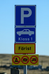 Signage informs drivers about parking rules for cars and restrictions for other vehicles in a rural location under clear blue skies
