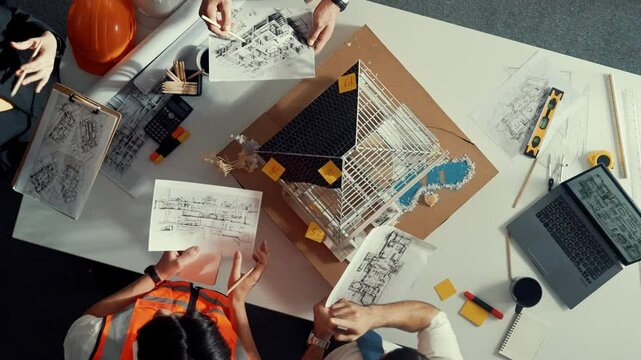 Top view of manager handed blueprint to professional engineer team at meeting table with house model and project plan. Group of architect discussing about design while receive document. Alimentation.