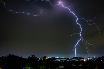 A dramatic photograph capturing powerful lightning strikes illuminating the dark sky. The jagged...