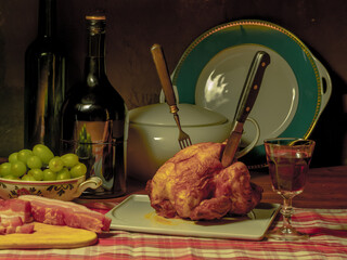 A stylized antique still life with a grilled chicken, a glass of red wine and lard.