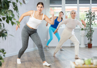 Fototapeta premium Group of positive women who care about their physical health practice active dancing during a workout in a fitness studio