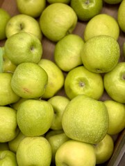 Box filled with fresh juicy natural bio organic green apples placed on counter in local food market