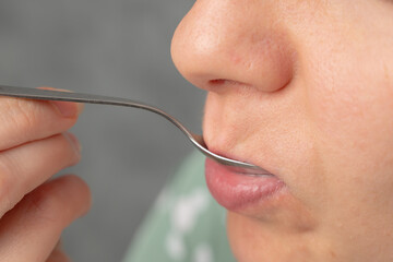 A close-up of a person bringing a fork to their mouth, focusing on the lips and fork.