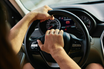 Hands gripping a steering wheel while driving a car with a focus on the dashboard and speedometer