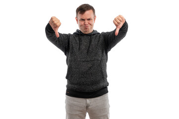 A young man in a gray hoodie making a thumbs down gesture against a white background.