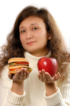 Young Woman Offering a Hamburger and an Apple