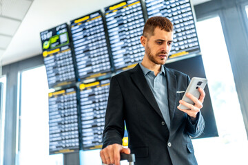 Businessman using smartphone at airport checking flight schedule