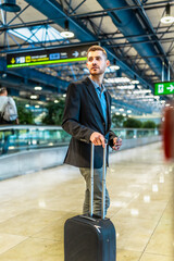 Fototapeta premium Businessman walking with trolley suitcase in airport terminal