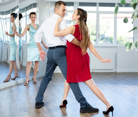 Couple learns dancing during individual lesson in classical and modern dance studio. Young girl...