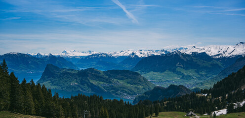 Breathtaking panoramic view from Mount Pilatus, showcasing the Swiss Alps, green valleys, and deep blue lakes under a clear sky. A perfect destination for nature lovers and hikers.