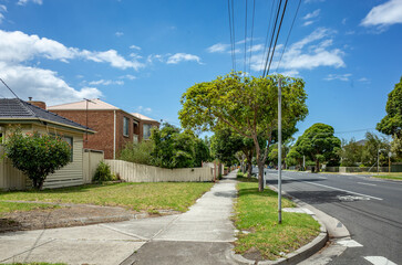a quiet suburban street featuring a concrete sidewalk leading past a modest residential house by a...