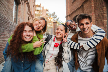 Diverse group of happy high school students posing outdoors, smiling and enjoying time together,...