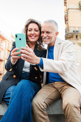 Happy mature couple booking their vacations or looking for directions with a smartphone while...