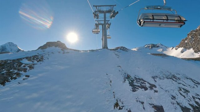 Riding chairlift in winter ski resort of Kaprun in Austrian Alps. Revealing beautiful views of snowy slopes of alpine mountains in sunny day